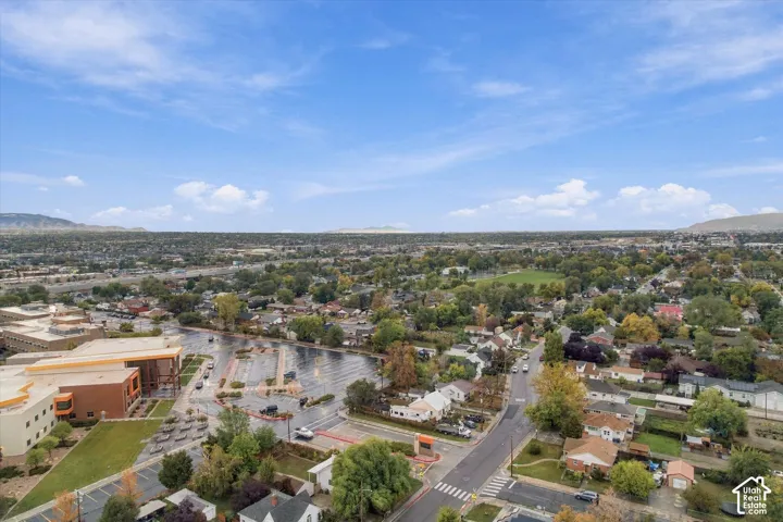 Aerial perspective of the surrounding landscape featuring expansive horizon lines, scattered mature trees, paved roadways, and mountain silhouettes in the distance