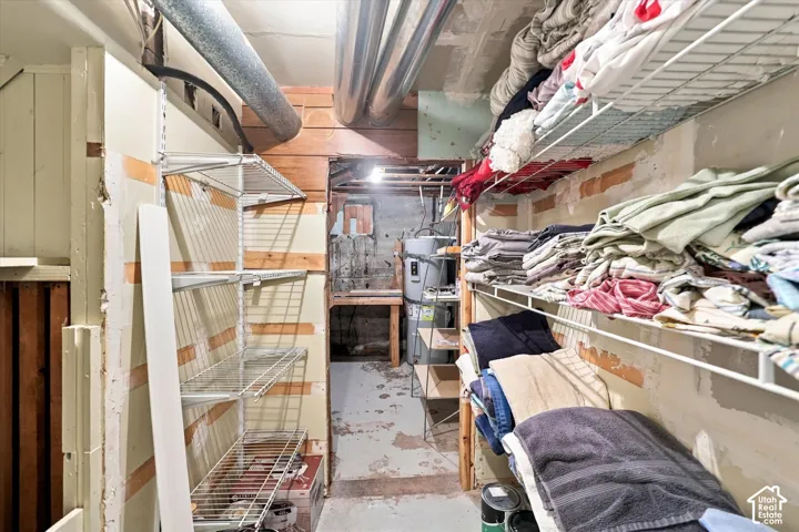 Utility room featuring metal wire shelving, exposed wood paneling, and an interior water heater