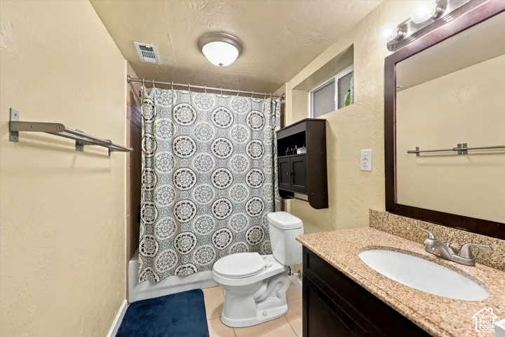 Bathroom featuring a dark wood-finish vanity, stone-patterned countertop, drop-in sink, mounted mirror, and a built-in wall cabinet