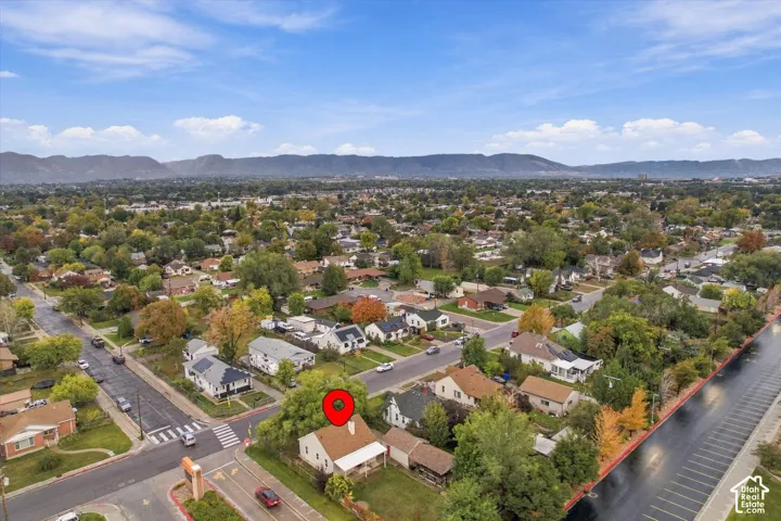 Aerial perspective featuring a property with a pitched roof, front porch, and a backdrop of mountain scenery