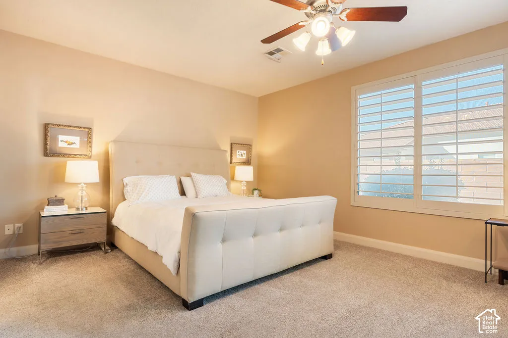 Ceiling fan with light fixture, window with plantation shutters, wall-to-wall carpeting, and neutral wall tones