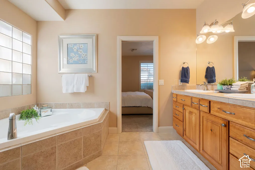 Corner soaking tub with tile surround, glass block window, double vanity with wood cabinetry, and dual undermount sinks