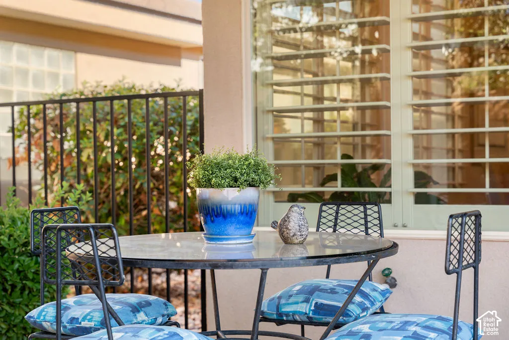 Exterior patio with a glass-top table, black metal railing, and privacy windows
