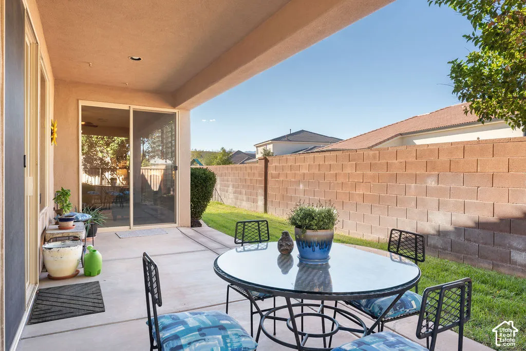 Covered patio with concrete flooring, sliding glass door, and a block wall perimeter