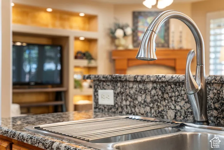 Stainless steel sink with a high-arc faucet, granite countertops, and wood-finish cabinetry