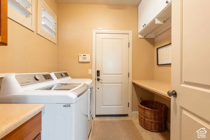 Dedicated laundry area featuring white plantation shutters, built-in cabinetry, a built-in countertop, and neutral-toned flooring