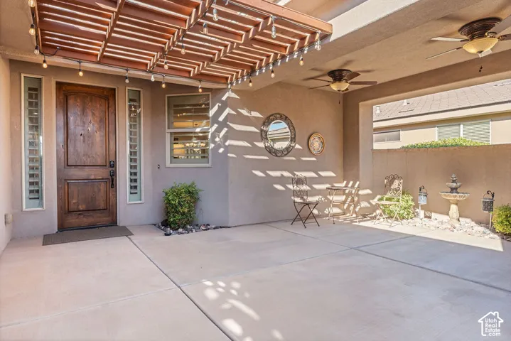 Covered patio with a wood pergola, ceiling fans, and concrete flooring