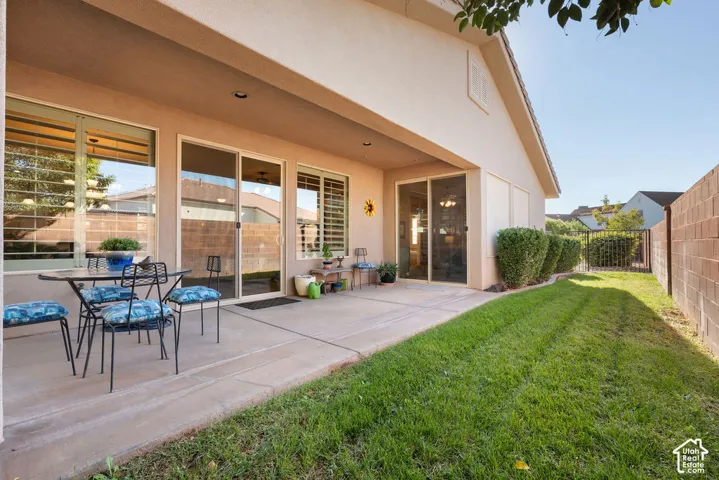 Covered patio with a concrete slab, multiple sliding glass doors, and manicured lawn