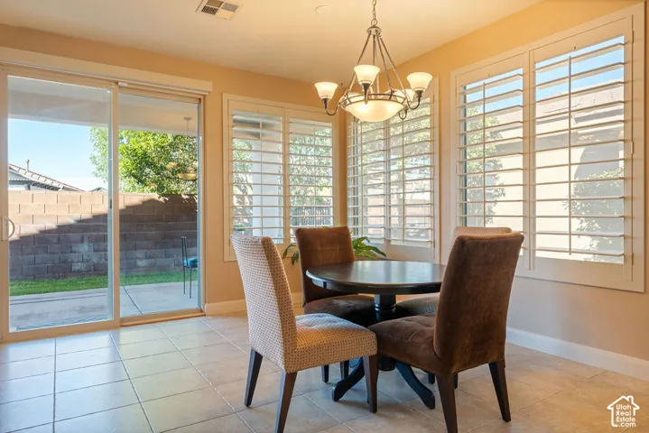 Ceramic tile flooring, white plantation shutters, sliding glass door, and a multi-light chandelier