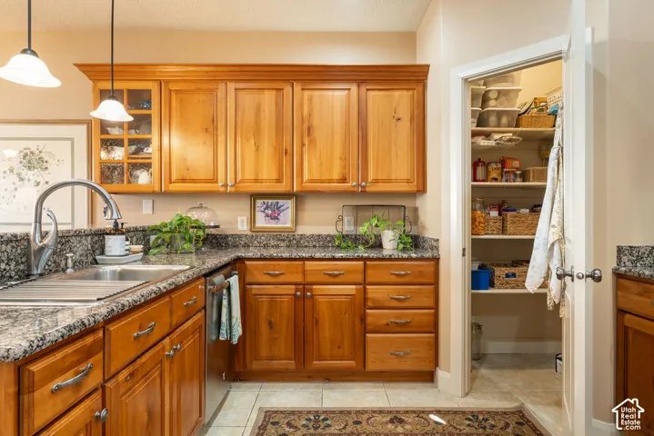 Kitchen featuring wood cabinetry, granite countertops, stainless steel sink, and tile flooring