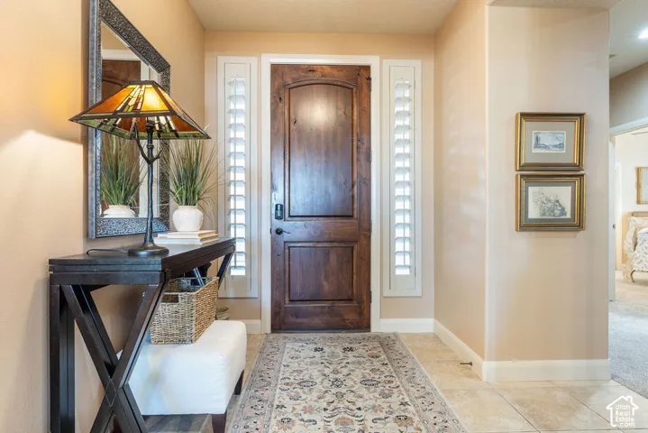 Solid wood-paneled entry door with sidelights, neutral wall tones, and floor tiling