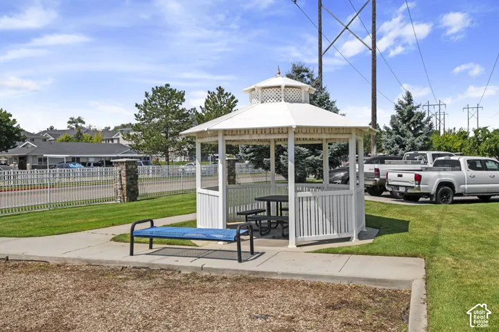 White gazebo with a multi-tiered roof, surrounded by a paved path and green lawn
