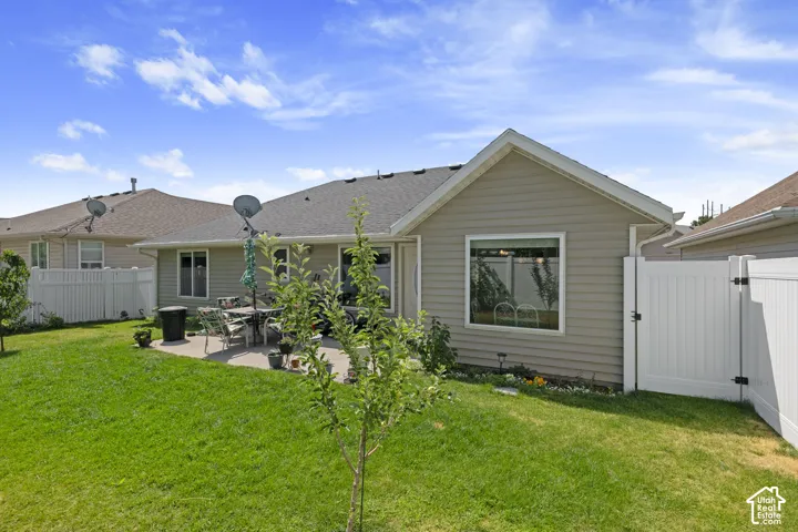 Expansive backyard with a concrete patio, vinyl siding exterior, and white vinyl privacy fencing