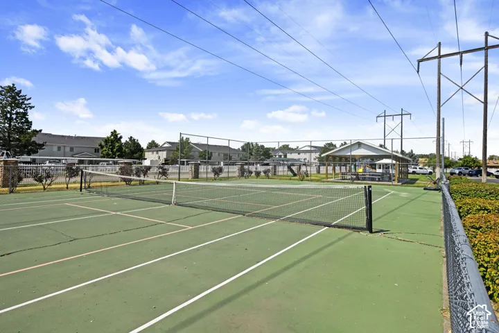 Tennis court with a net, perimeter fencing, and a shaded outdoor pavilion