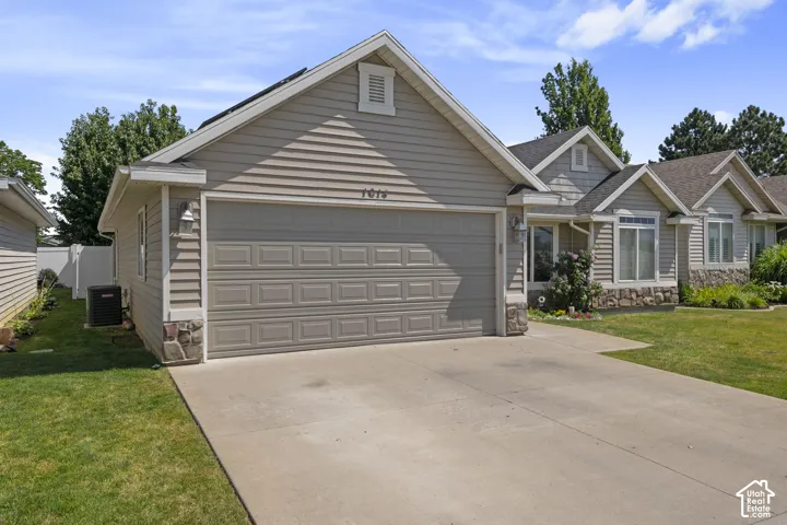 Light-toned siding exterior with stone accents, an attached garage, and a concrete driveway