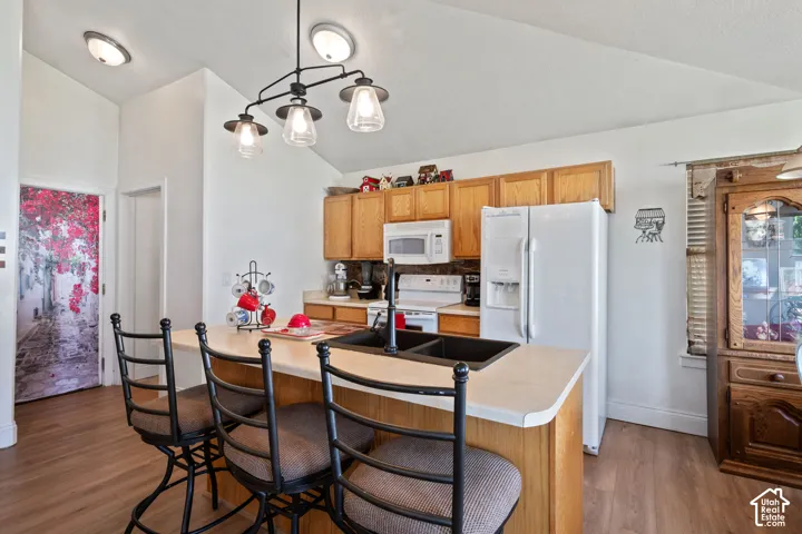 Kitchen featuring a breakfast bar with seating, wood-finish cabinetry, a double basin sink, and integrated overhead lighting