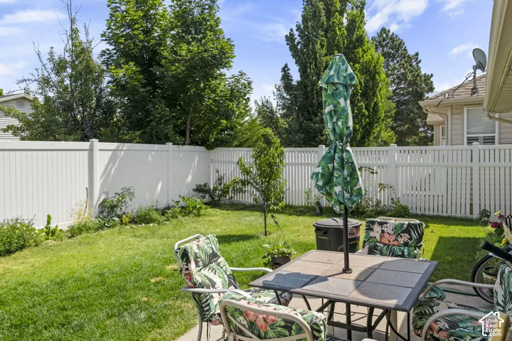 Expansive green lawn with a white privacy fence and established trees