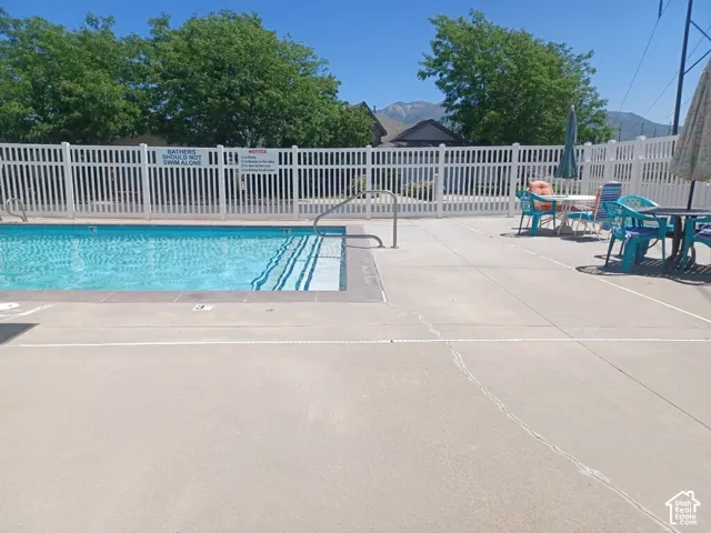 Outdoor swimming pool with integrated steps, surrounded by a white picket fence, and a concrete deck