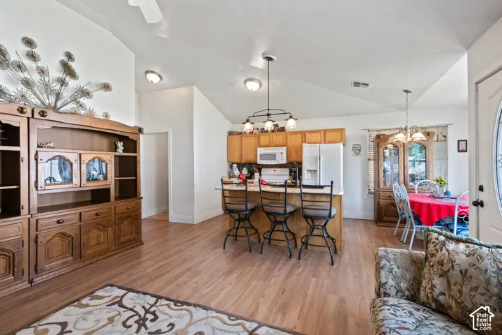 Vaulted ceilings with recessed lighting, wood-finish flooring, kitchen island with breakfast bar, built-in cabinetry, and a dining area