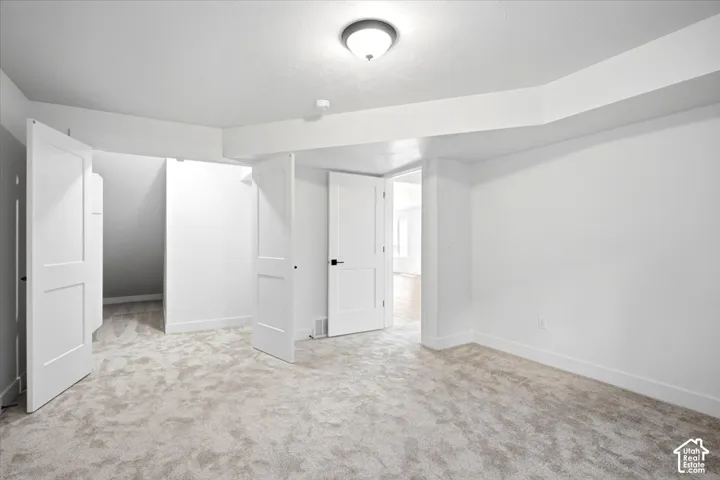 Neutral toned carpeted flooring, white walls, and a semi-flush mount ceiling light fixture