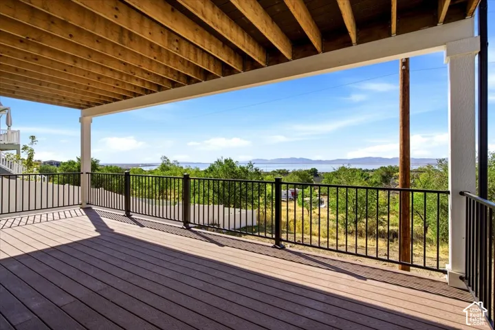 Covered deck with composite flooring, black metal railing, and exposed wood ceiling joists
