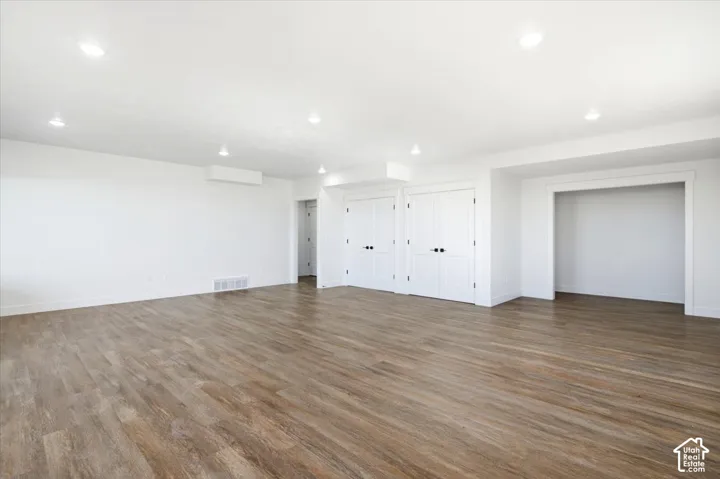 Spacious room featuring wood-finish flooring, recessed lighting, and crisp white walls