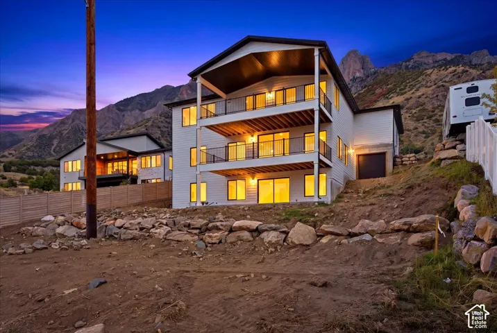 Multi-level residence featuring white siding, multiple balconies with black railings, and a lower-level garage