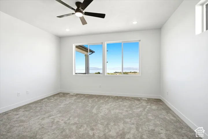Carpeted room featuring large windows, a ceiling fan with integrated lighting, and recessed ceiling lights