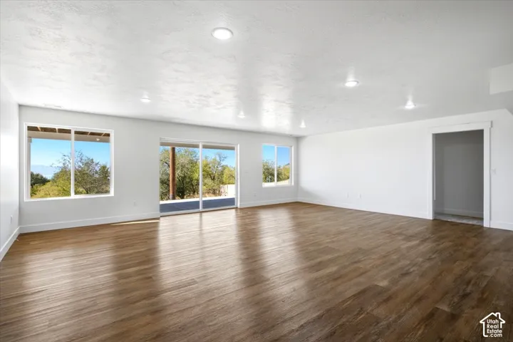 Spacious room featuring wood-finish flooring, recessed lighting, and large windows with a sliding glass door
