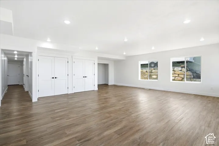Recessed lighting, wood-finish flooring, white walls, multiple windows, and white interior doors