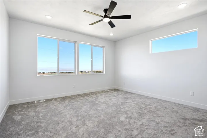 Recessed lighting, ceiling fan, white walls, gray carpet flooring, multiple windows