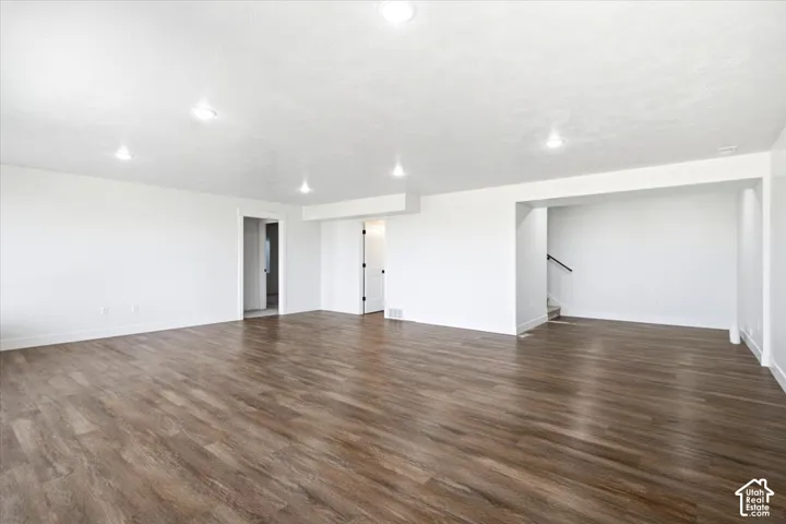 Spacious room featuring wood-finish flooring, recessed lighting, and white walls