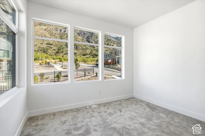 Multiple large windows, neutral color palette, new wall-to-wall carpeting, white trim, and a mountain backdrop