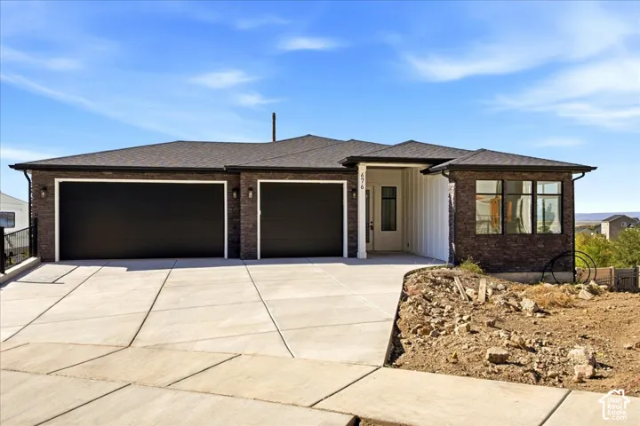 Contemporary single-story residence featuring a dark brick exterior, two-car garage with dark doors, and a concrete driveway
