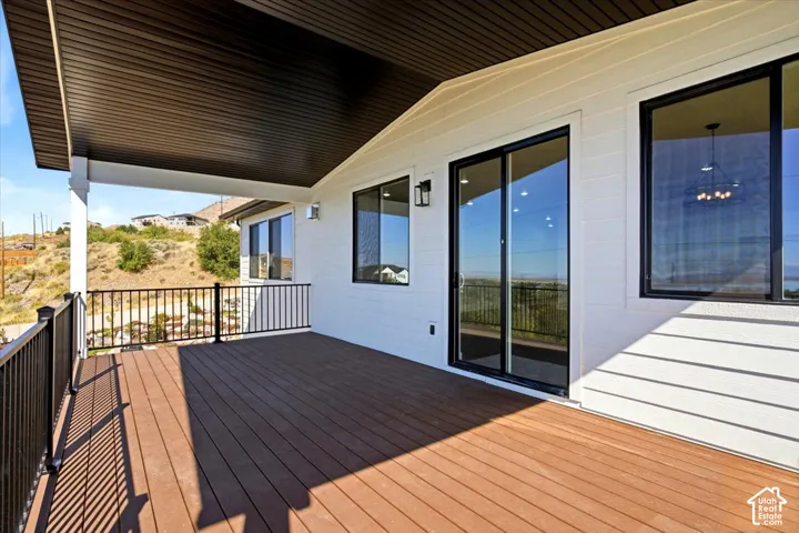 Expansive covered deck featuring wood-finish decking, black metal railings, and white siding