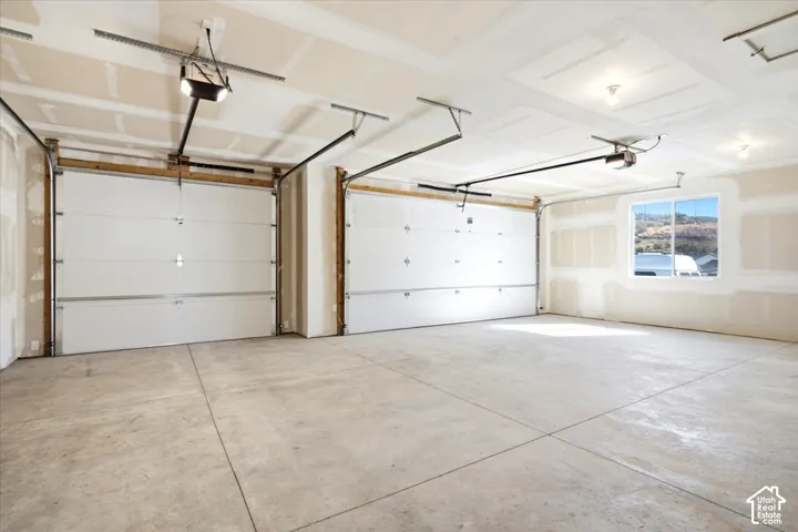 Two-car garage featuring automatic garage door openers, concrete flooring, and a large window