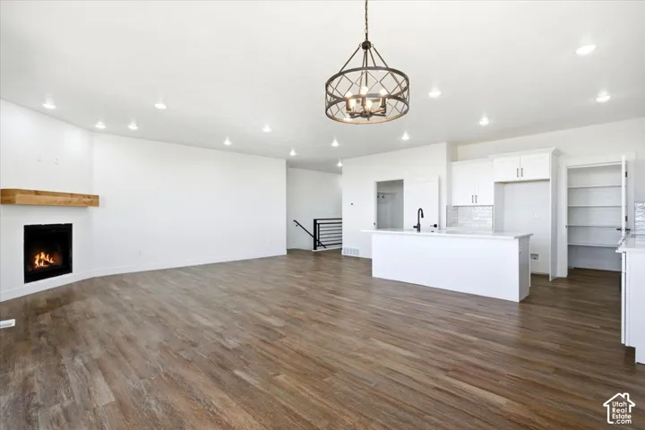 Spacious open-concept living area featuring wood-finish flooring, recessed lighting, and a corner fireplace with a wood mantle