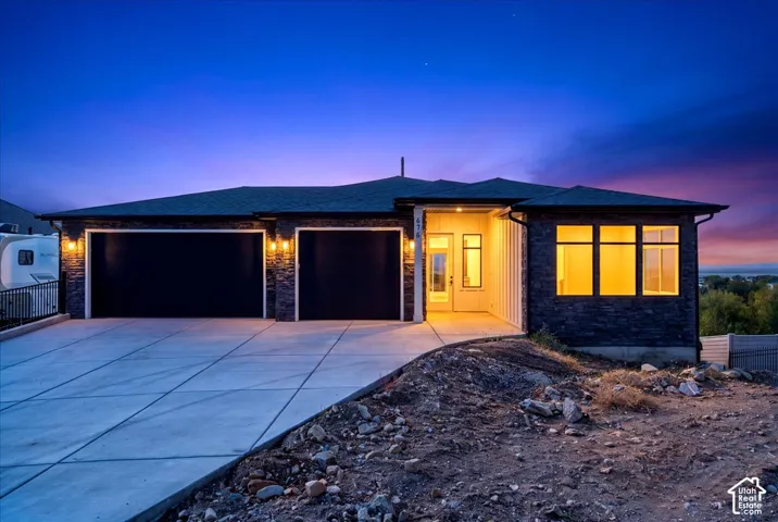 Stone veneer and vertical siding exterior, two-car garage, concrete driveway, prominent front entry, and multiple windows
