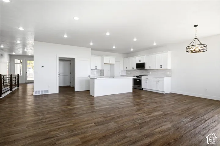 Open concept living space with wood-finish flooring, recessed lighting, and a modern kitchen featuring white cabinetry, a kitchen island, and stainless steel appliances