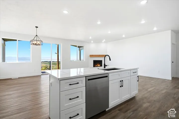 Kitchen island with white cabinetry, stainless steel dishwasher, and a black sink with a matte black faucet