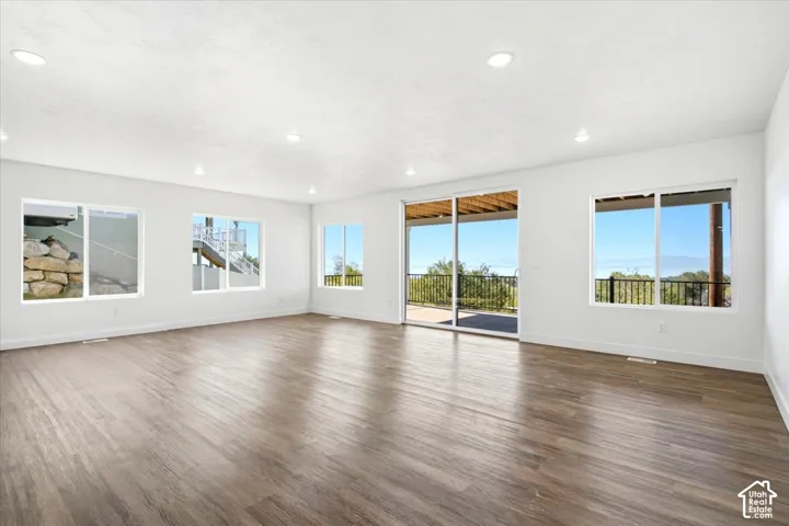 Spacious room featuring wood-finish flooring, recessed lighting, and multiple windows