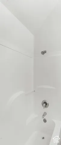 White seamless tub and surround featuring a polished chrome shower head, single-handle mixing valve, and spout