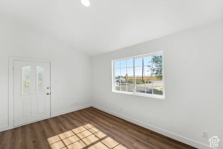 Bright interior featuring wood-finish flooring, white walls, a white entry door with decorative glass inserts, and a large window with white framing