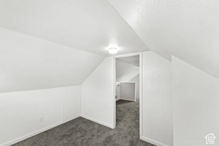 Carpeted room with sloped ceilings, white walls, and a ceiling-mounted light fixture
