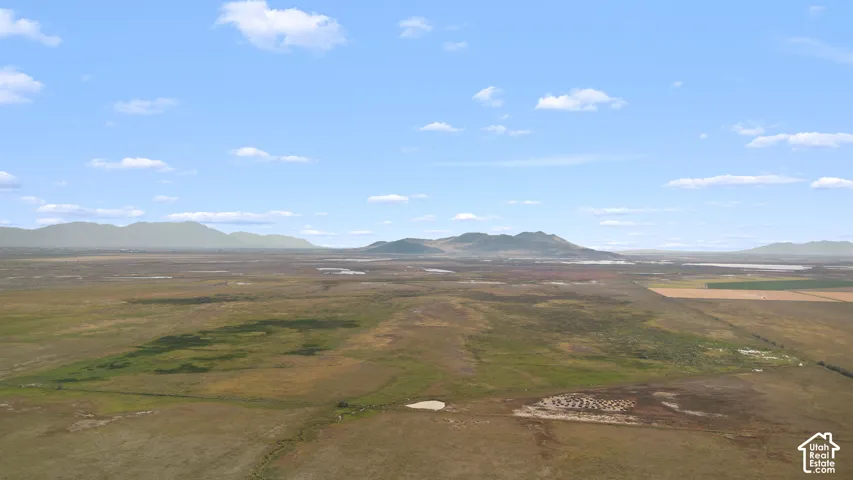Expansive open terrain with distant mountains under a blue sky