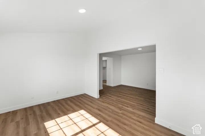 Wood-finish flooring throughout, recessed ceiling lighting, and an open entryway to an additional room