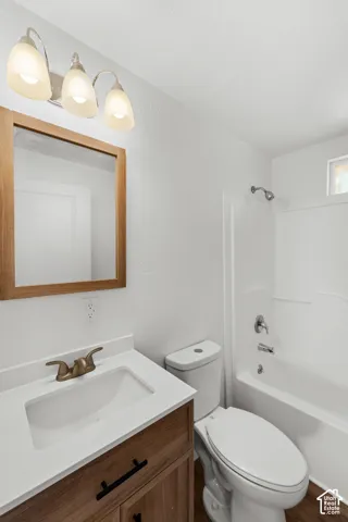 Bathroom featuring a wood-finish vanity with a white countertop, an integrated sink, a bronze-finish faucet, and a framed mirror