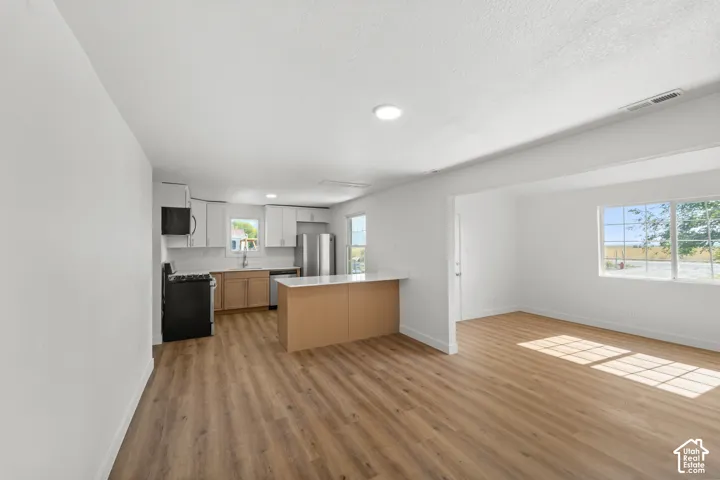 Open-concept living space featuring wood-finish flooring, recessed lighting, and a kitchen island with a white countertop
