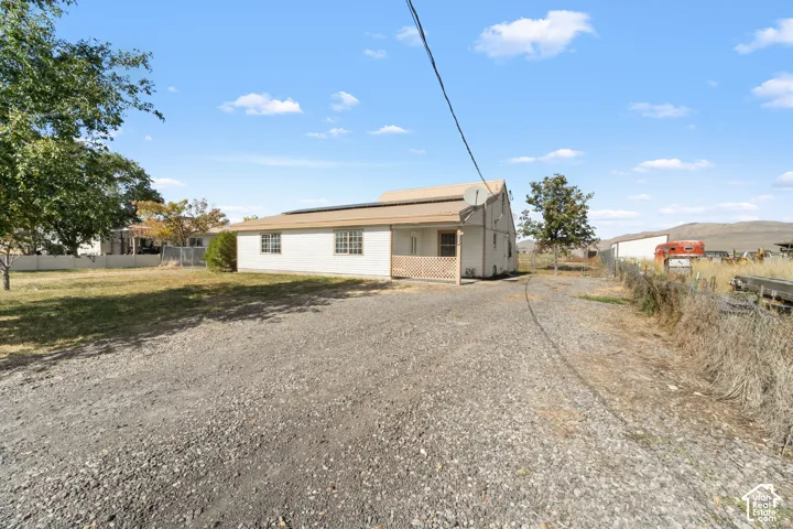Gravel driveway extending to a single-story structure with a covered porch and white siding