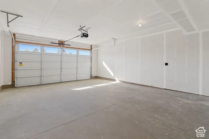 Two-car garage featuring a sectional overhead door with upper transom windows, concrete flooring, and an automatic door opener